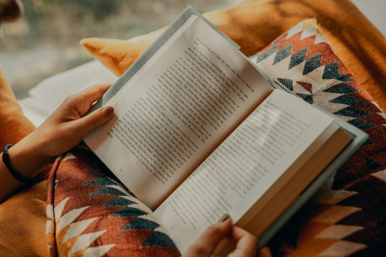 Person holding a book open set against a pillo